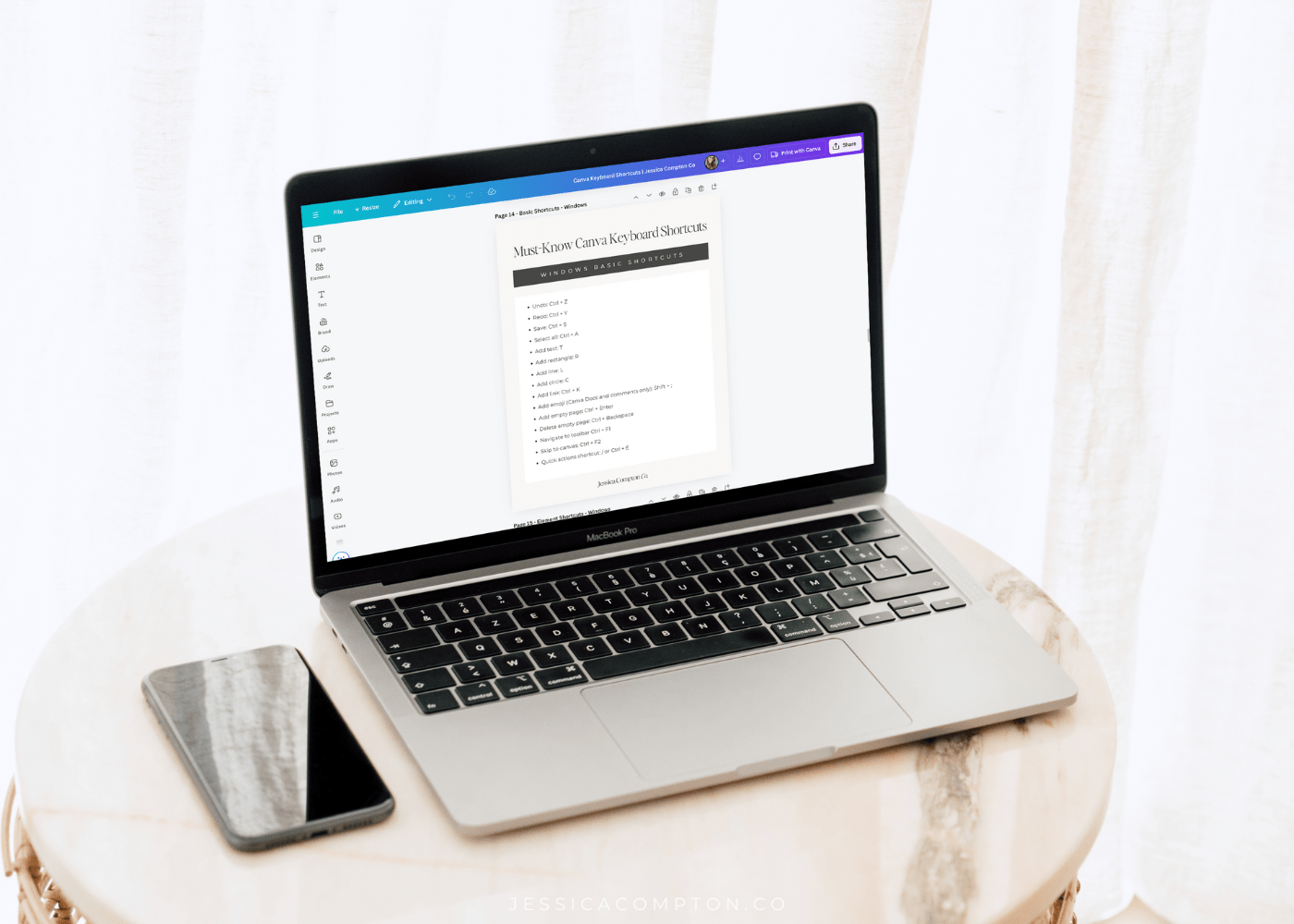 PDF freebie for Canva Keyboard shortcuts displayed on laptop screen on a small table next to phone